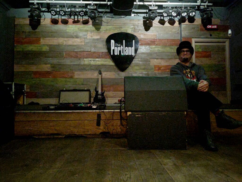 Rishi posing next to a monitor in the Portland Arms gig room